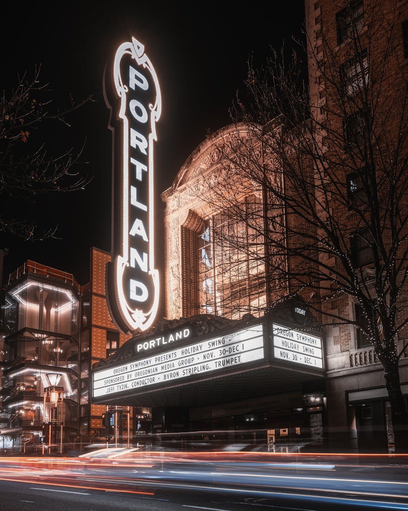 Long exposure photo of Portland theater with light trails and illuminated signage at night.